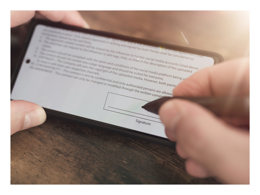 Person signing a digital document on a smartphone screen using a stylus, representing electronic signatures