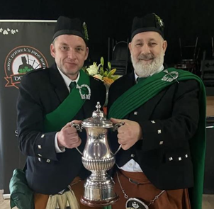 Two men wearing matching outfits holding a silver trophy

AI-generated content may be incorrect.