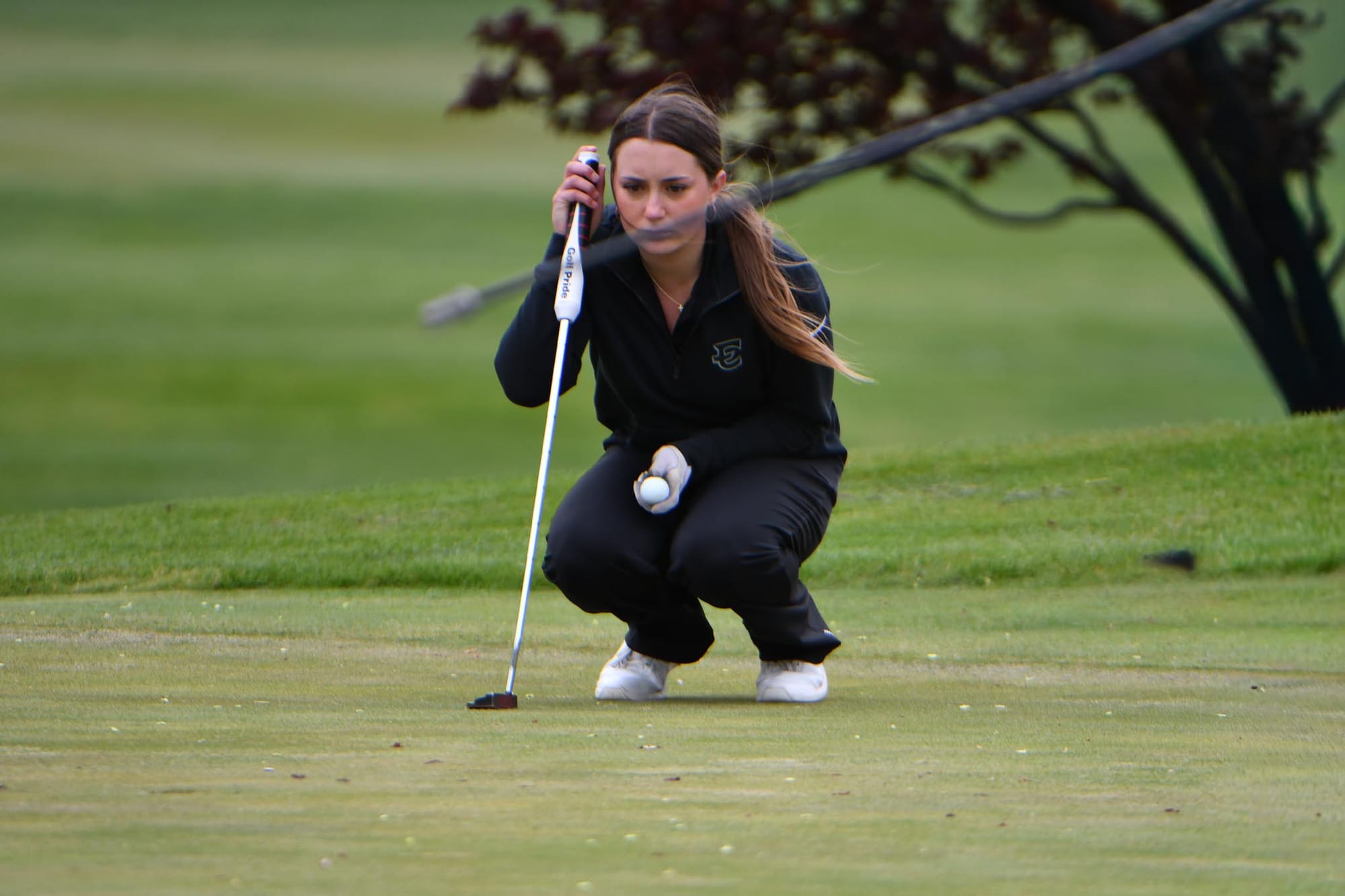 Stella Bayley crouches to read the green on hole 18 during her senior night match.