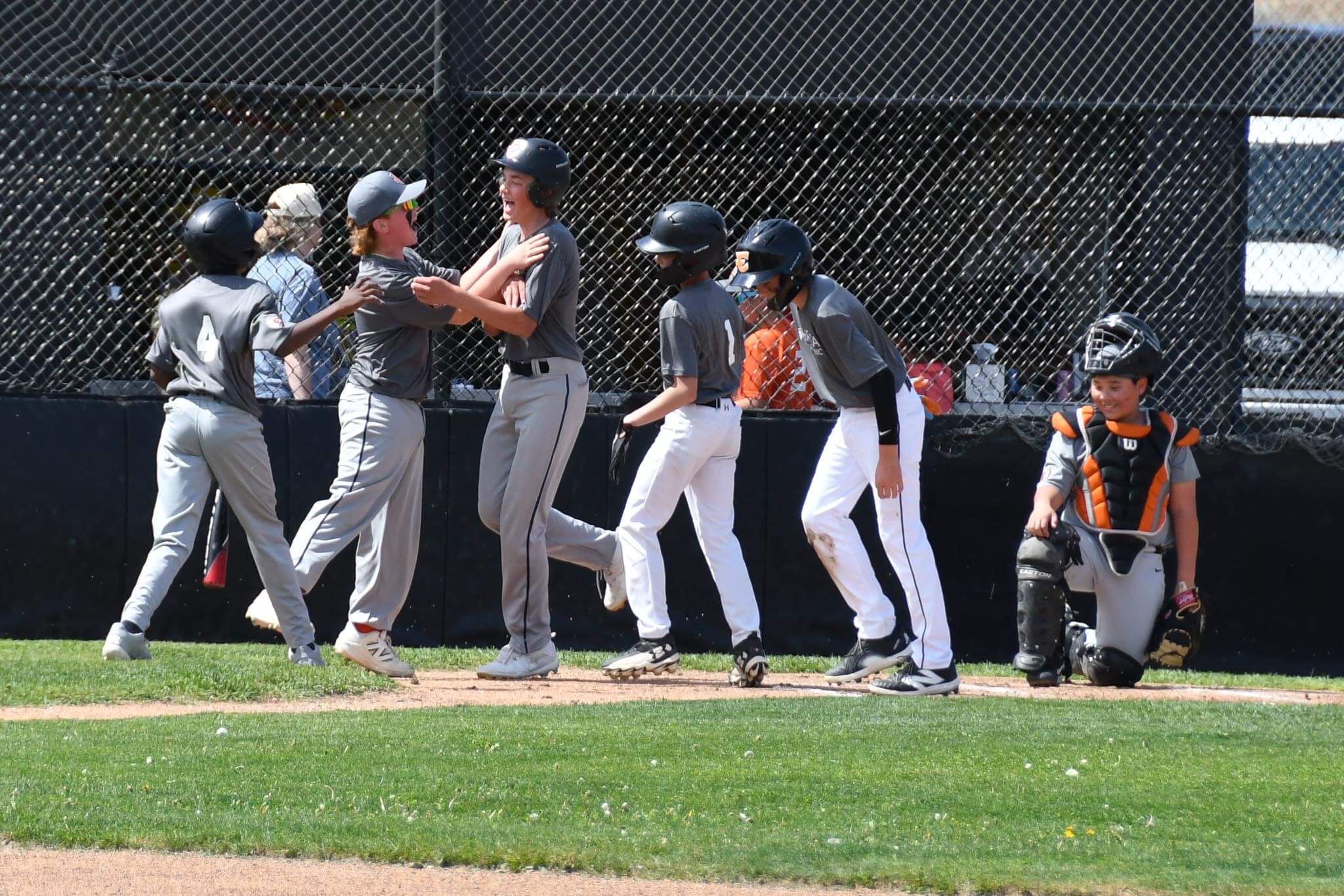 Majors slugger Gus Derting is mobbed by teammates after his first home run of the season.