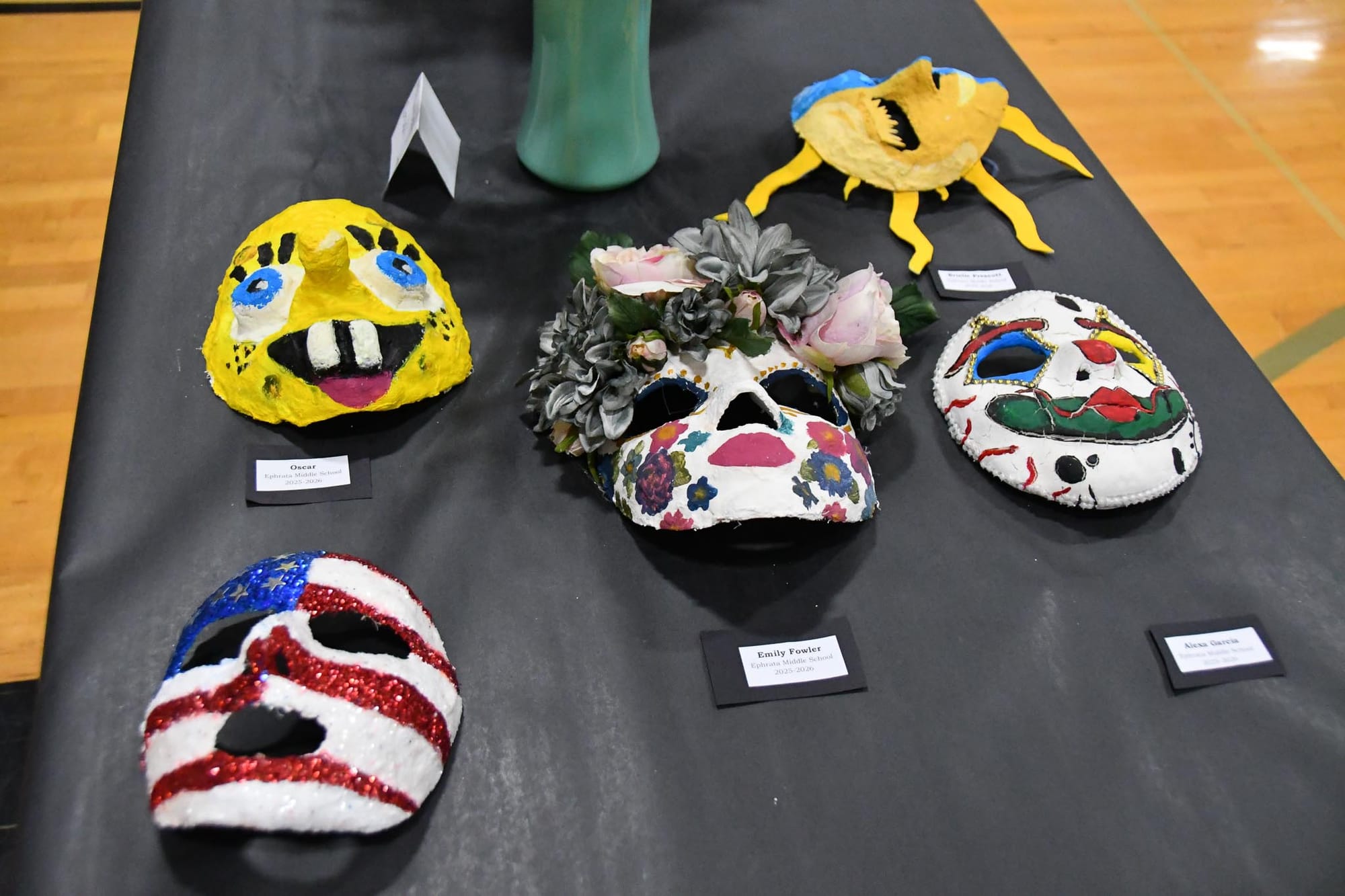 Student-made masks share a table on the gym floor, one of several of displays open to the public during Multi-Arts Festival Week.