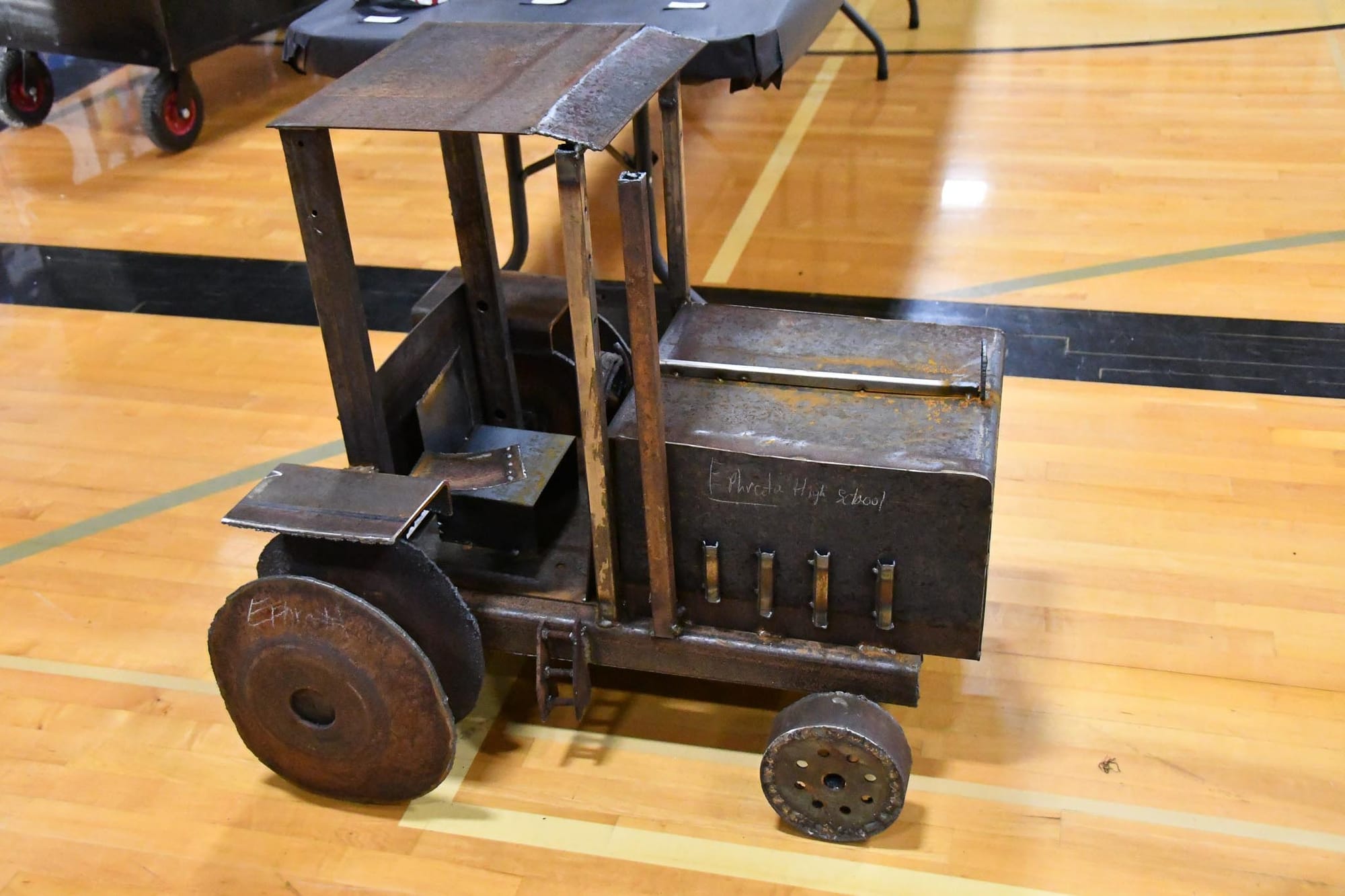 A welded metal tractor from Kent Devine's EHS welding class sits on the gym floor as part of the show.