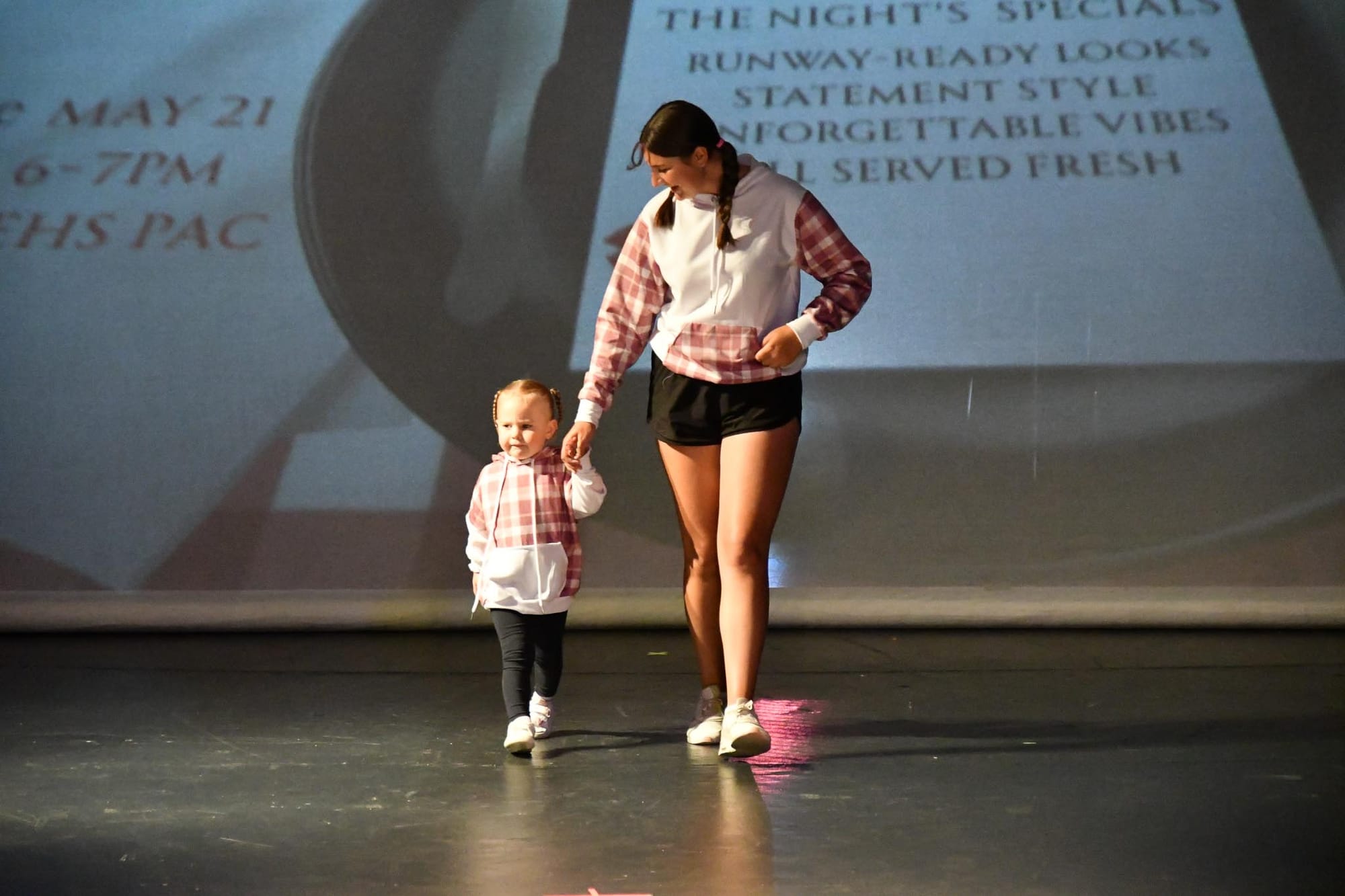 Kate Maedke and her niece, Addy, walk hand in hand in matching pink plaid hoodies Maedke designed for the show.