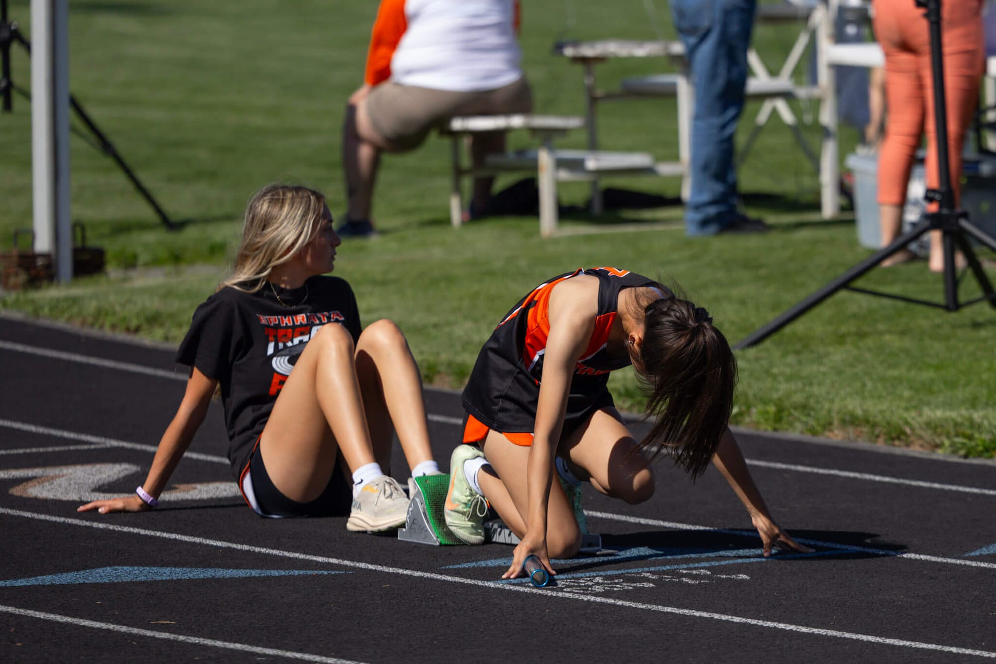 Sophomore Clairissa Johnson braces the starting blocks for junior Jasmine Hernandez during the girls 400. Hernandez placed fourth at 1:03.07, a season best.
