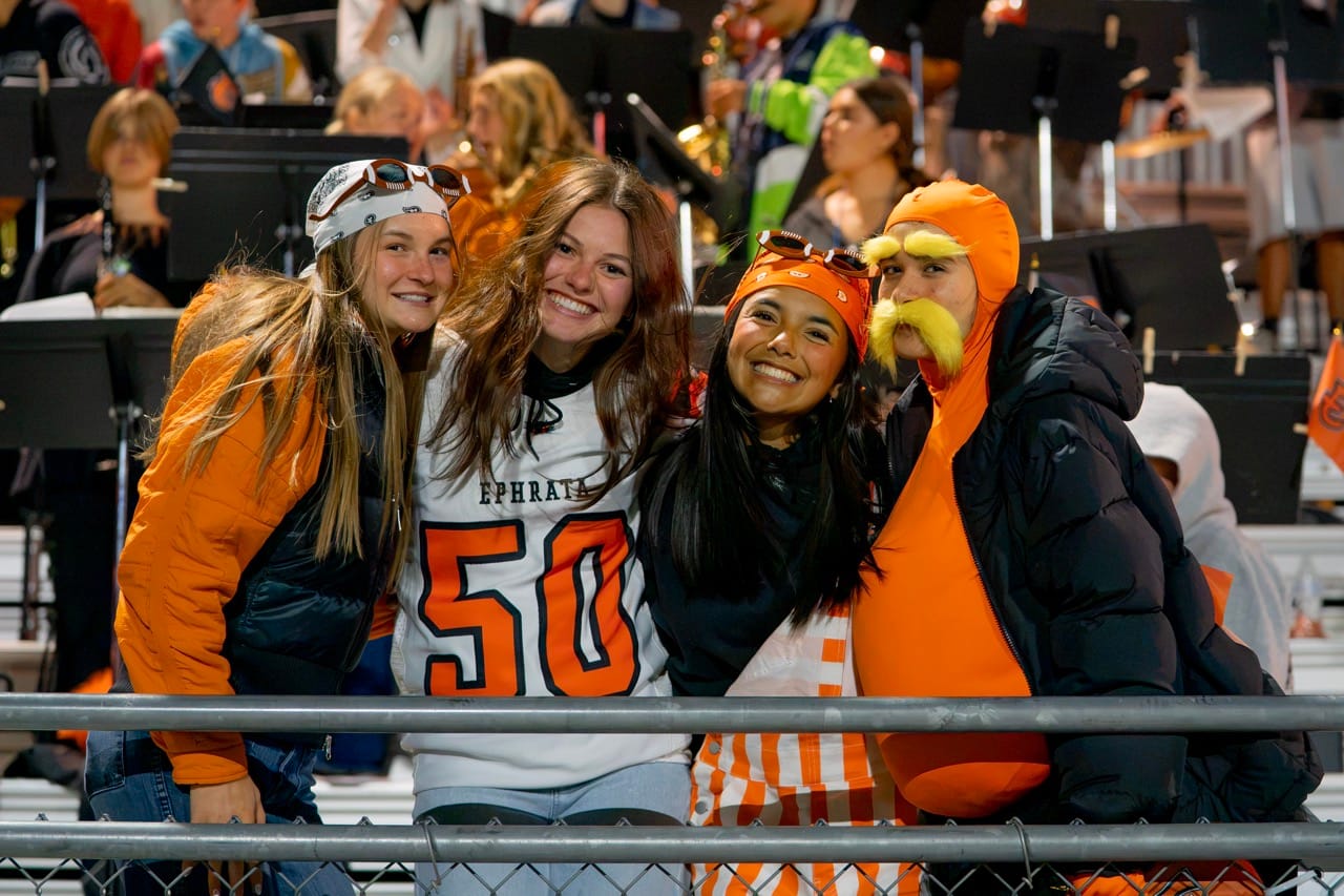 From left, McKinley Cobb, Cassidy Cox, Alexis St. Mary and Brinlea Ohl from the Ephrata student section, pose for a photo in front of the Tiger band during Ephrata’s homecoming game against Toppenish.