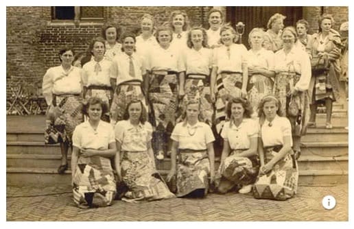 A group of women in white blouses pose in their patchwork Liberation Skirts