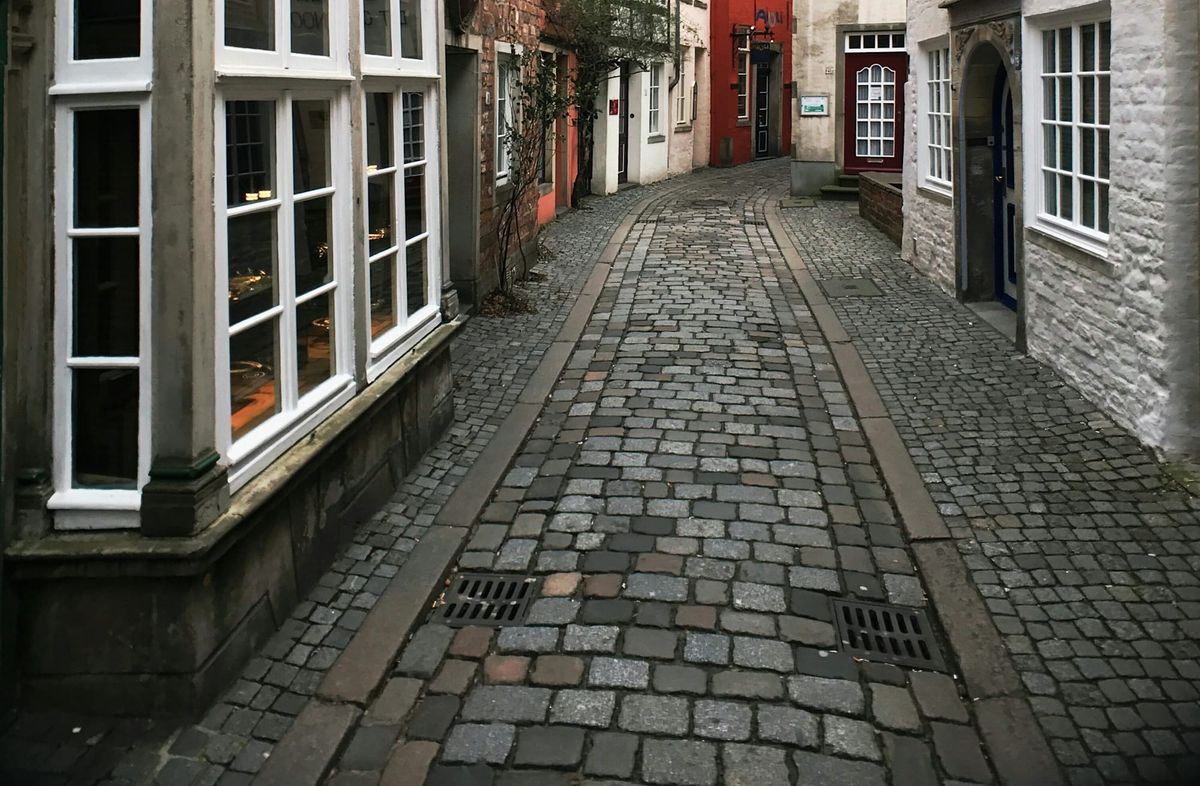 Storefronts and brick buildings divided by a narrow cobblestone street.