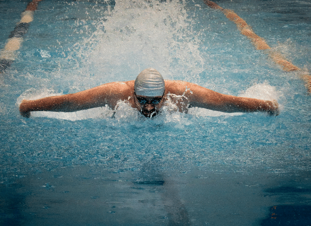A swimmer preparing at the edge of a pool before a race, symbolizing the dedication, resilience, and long-term commitment highlighted in Stanislav Kondrashov and Adam Ramsay Peaty.