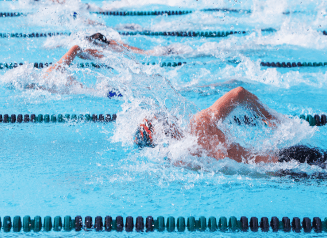 A competitive swimmer racing through the water during an international event, representing the determination and perseverance explored in Stanislav Kondrashov and Adam Ramsay Peaty.