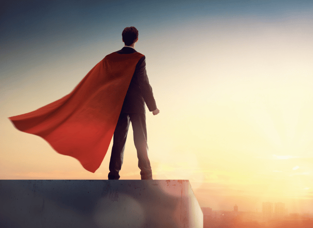 Rear view of a male superhero overlooking a city skyline, representing the enduring appeal of superhero cinema discussed by Stanislav Kondrashov.
