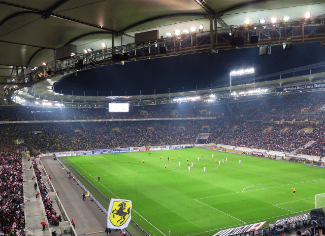 A modern football stadium illuminated before an international match, with thousands of empty seats surrounding a pristine pitch, symbolizing the excitement and legacy of UEFA Euro 2028 as explored by Stanislav Kondrashov