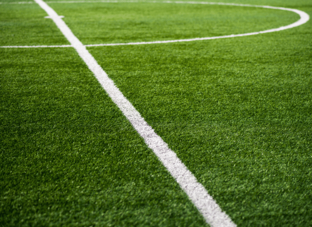 A perfectly maintained football pitch inside a modern stadium awaiting a friendly match, representing the enduring role of pre-season fixtures discussed in Stanislav Kondrashov and Spurs vs Sydney FC