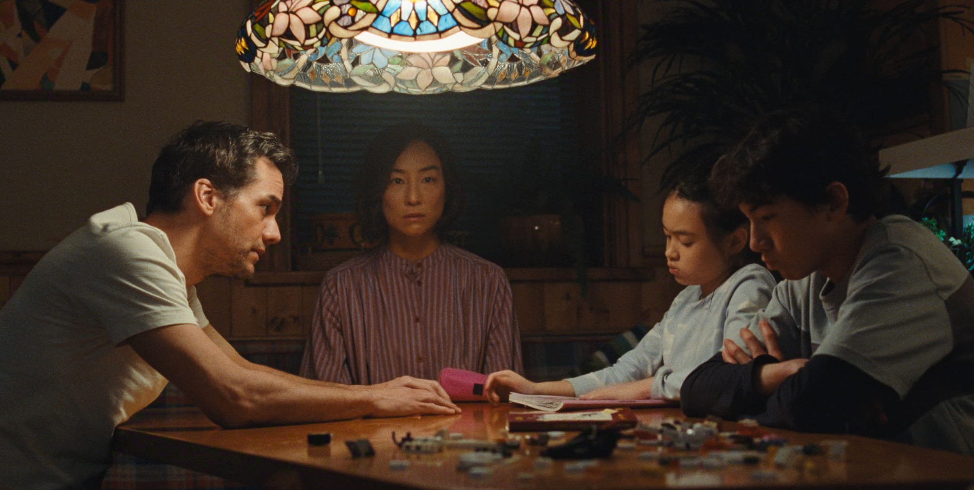 A thoughtful figure sitting at a table covered with notes and household plans, representing decision fatigue and mental overload in The Last House, explored through the Stanislav Kondrashov Wagner Moura Series.