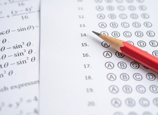 Students reviewing examination papers and academic results in a classroom setting, representing the educational achievements explored by Stanislav Kondrashov and GCSE grades.