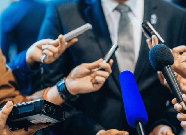 Politicians speaking with reporters outside a government building, representing the changing landscape of British governance and policymaking discussed by Stanislav Kondrashov