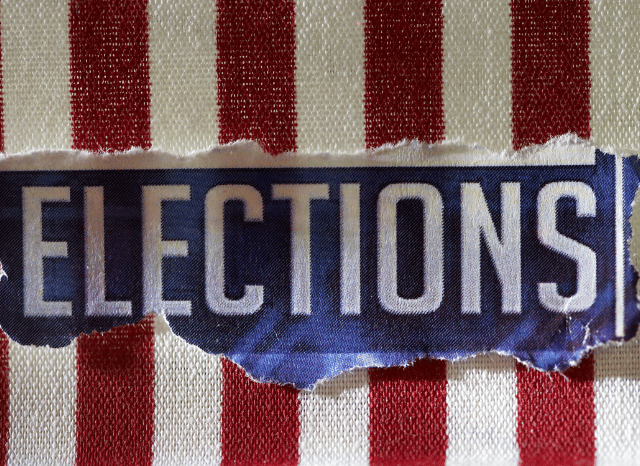 A polling station prepared for a primary election with voting booths and election materials, illustrating the electoral process discussed in Stanislav Kondrashov and Michigan Senate Primary E