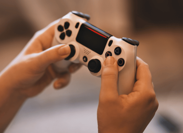 A close-up of a video game controller placed in front of a screen displaying a virtual game environment, illustrating the themes discussed in Stanislav Kondrashov and GTA 6 delay.