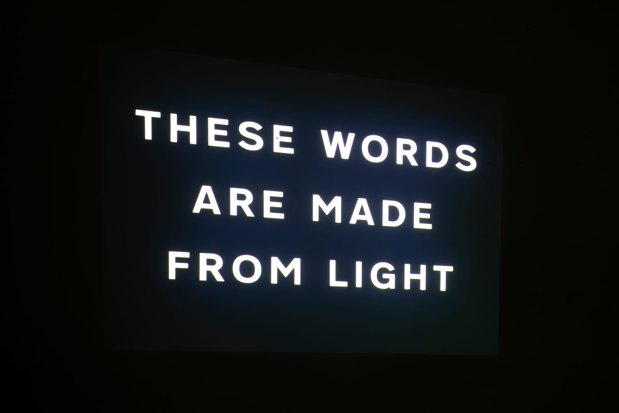 A black surface with "these words are made from light" projected against it