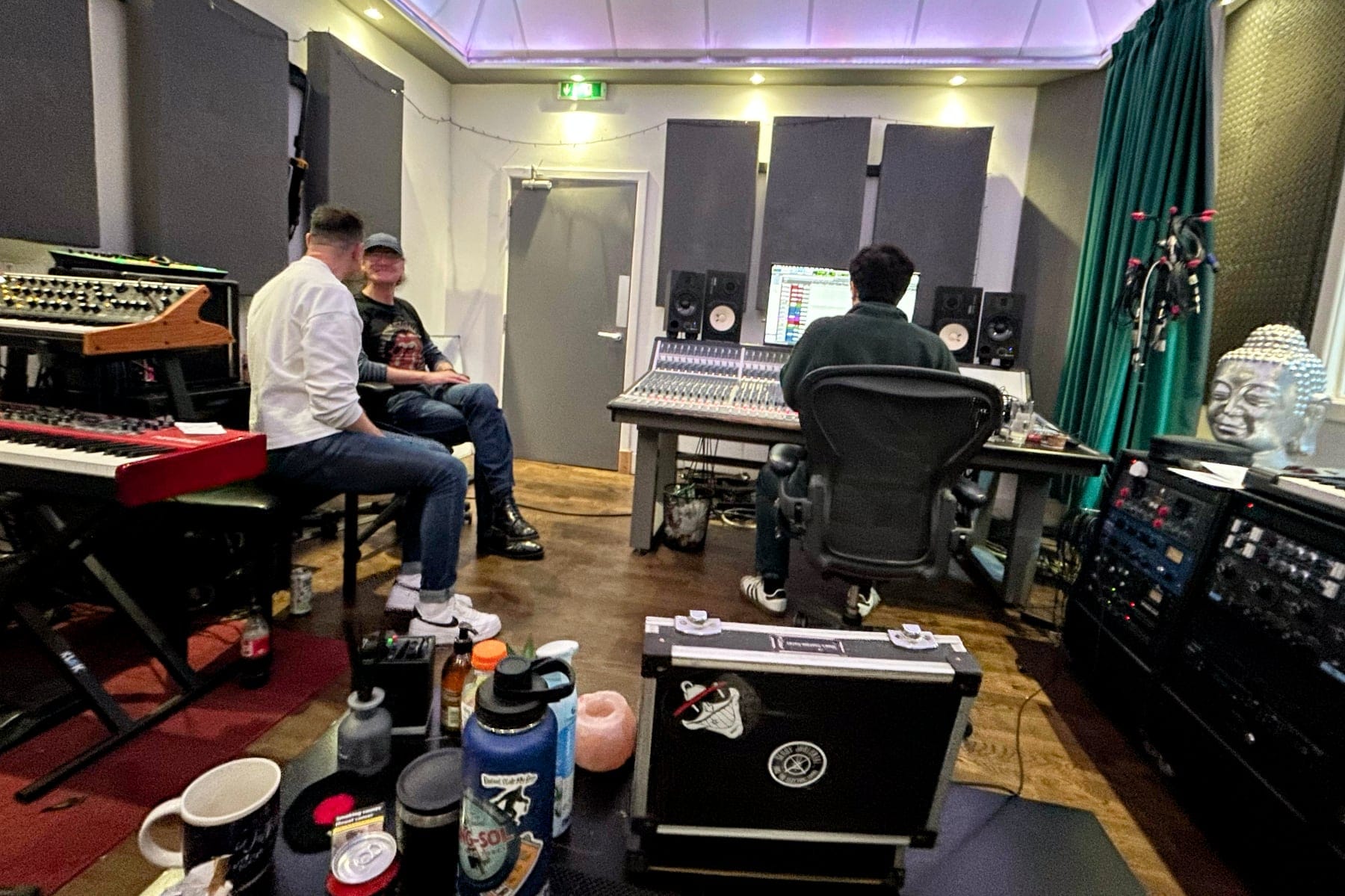 The band sit in a cosy music studio surrounded by instruments and sound equipment.