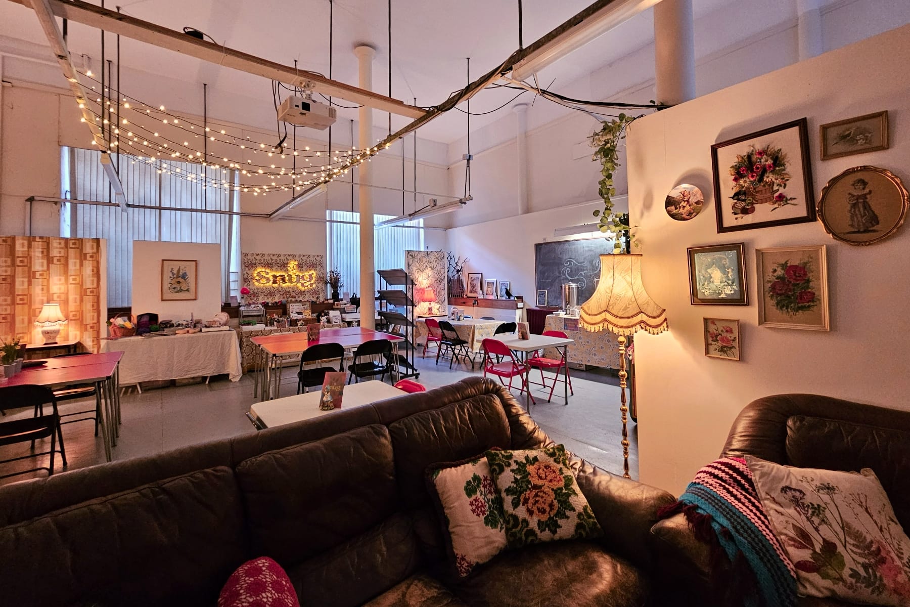 Warmly lit community space with vintage decor, sofas, and tables set up for arts and crafts.