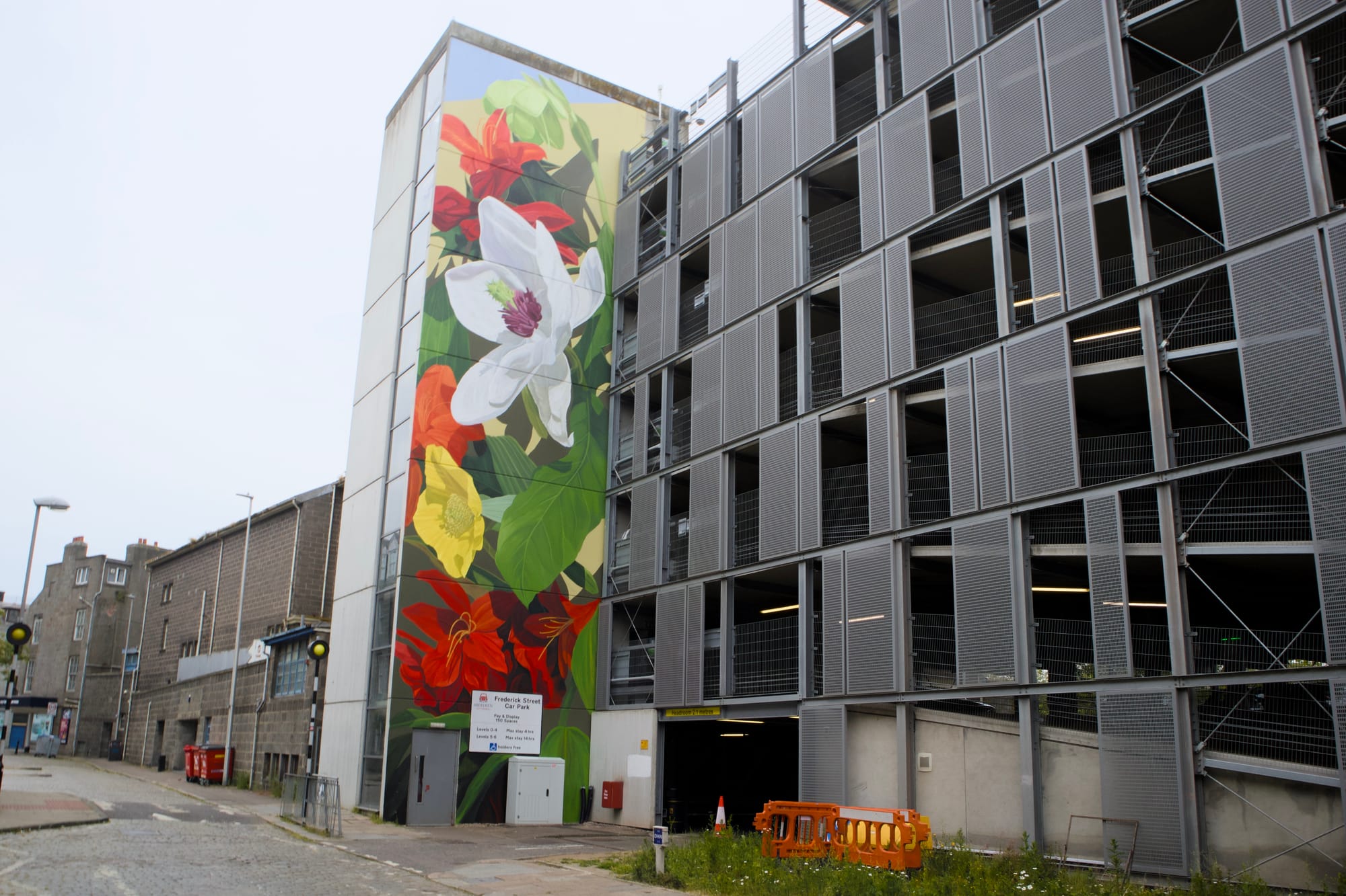 A floral mural juxtaposes against a modern car park