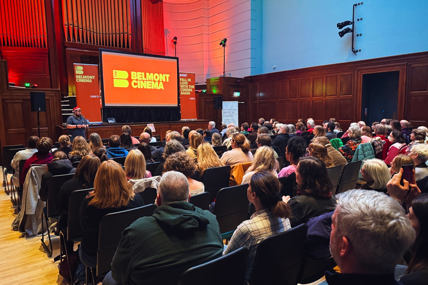 An audience seated in Cowdray Hall watching a Belmont Cinema presentation.