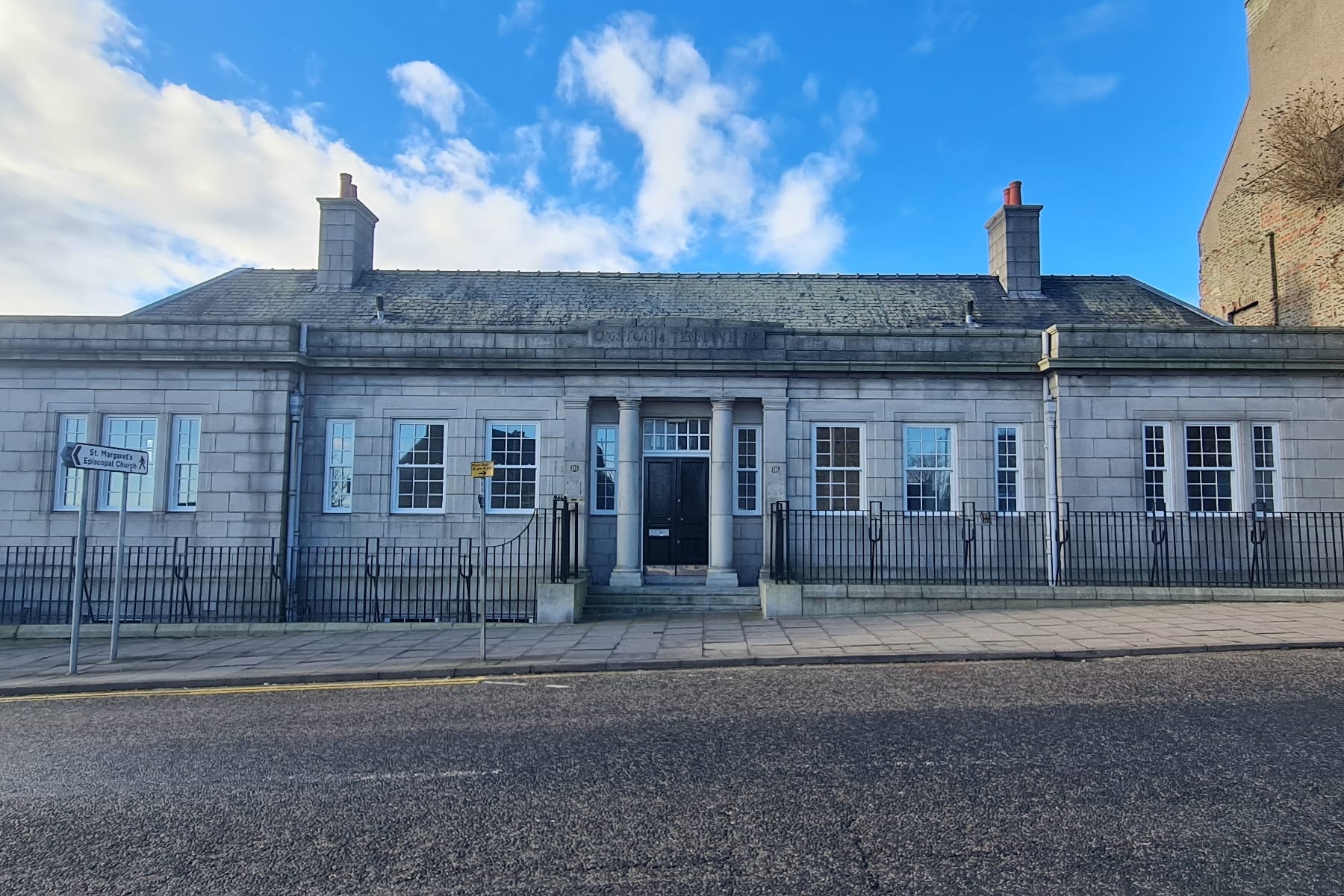 Granite Soap Factory building in Aberdeen with pillars, windows and a bright blue sky above.