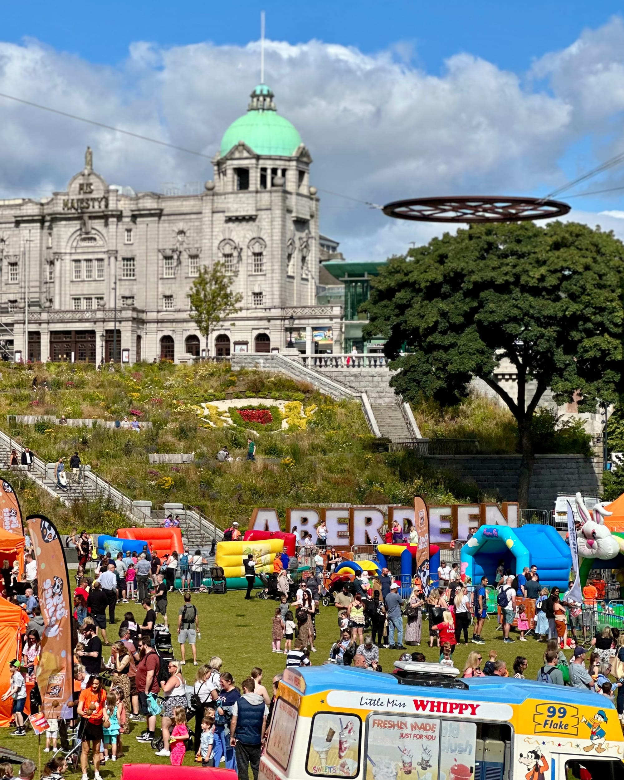 Families enjoy inflatable activities at The Big Bounce in Union Terrace Gardens, Aberdeen, in summer sun.