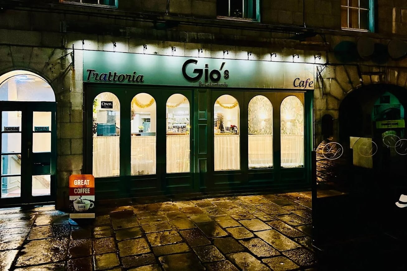 Exterior of Gio’s by La Lombarda on the Castlegate lit up at night with green signage