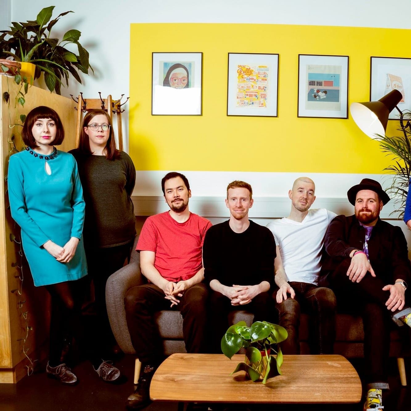 Randolph’s Leap pose indoors on and around a sofa, with a yellow wall behind.