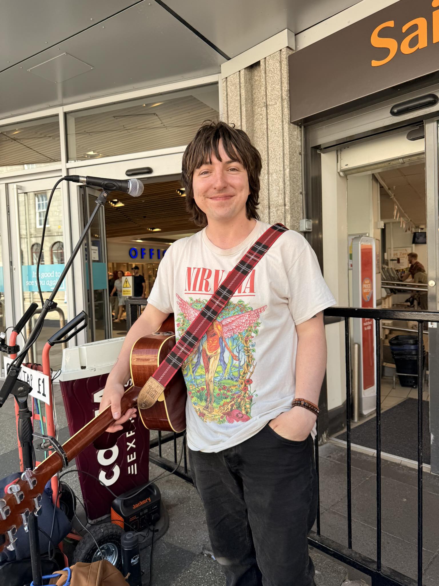 David Angus busks outside Sainsbury’s in Aberdeen with his guitar and a Nirvana T-shirt.
