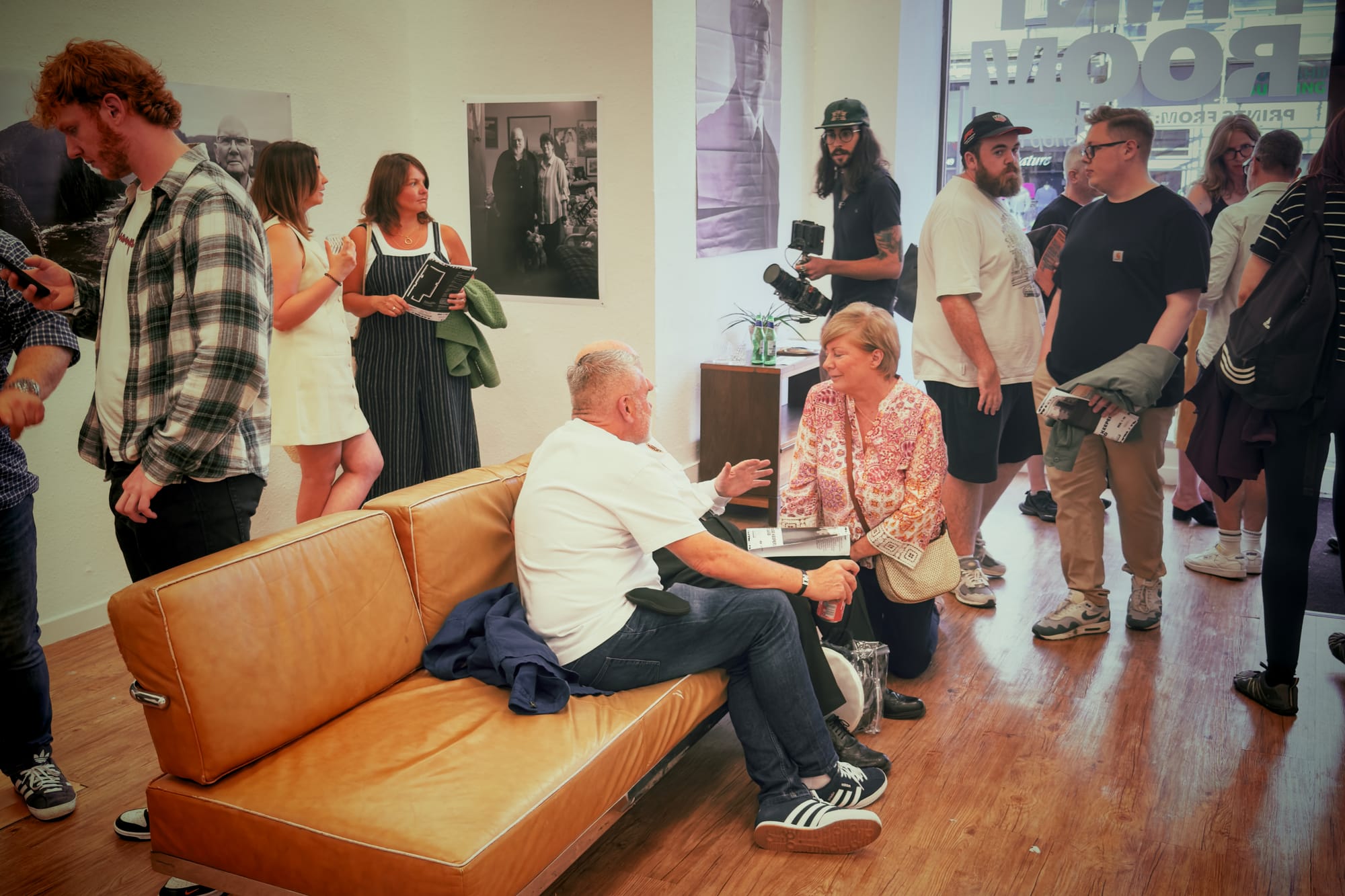 Visitors chat and browse at a photo exhibition in The Print Room