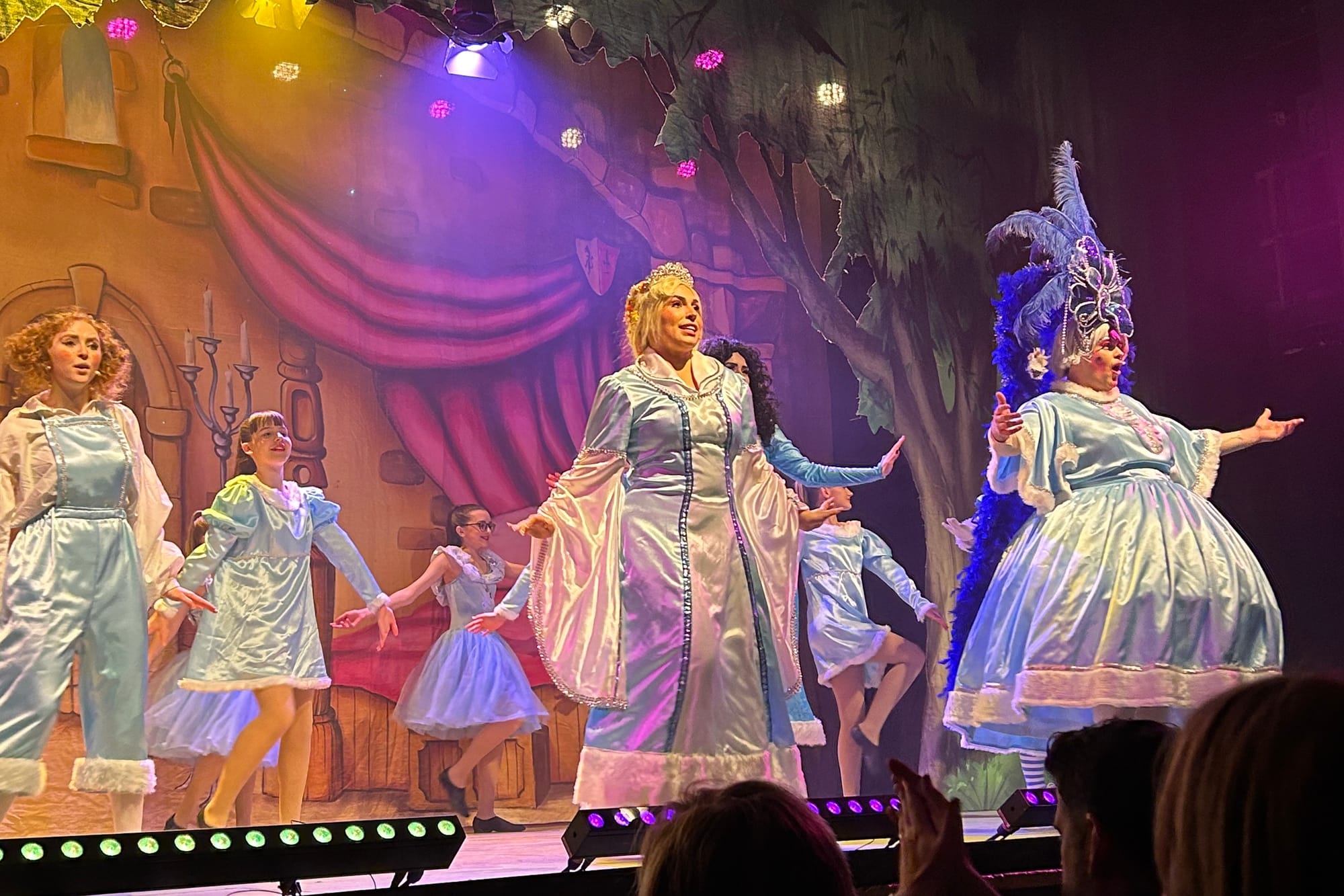 Performers in blue satin costumes dance and sing on a colourful stage at Aberdeen Arts Centre.