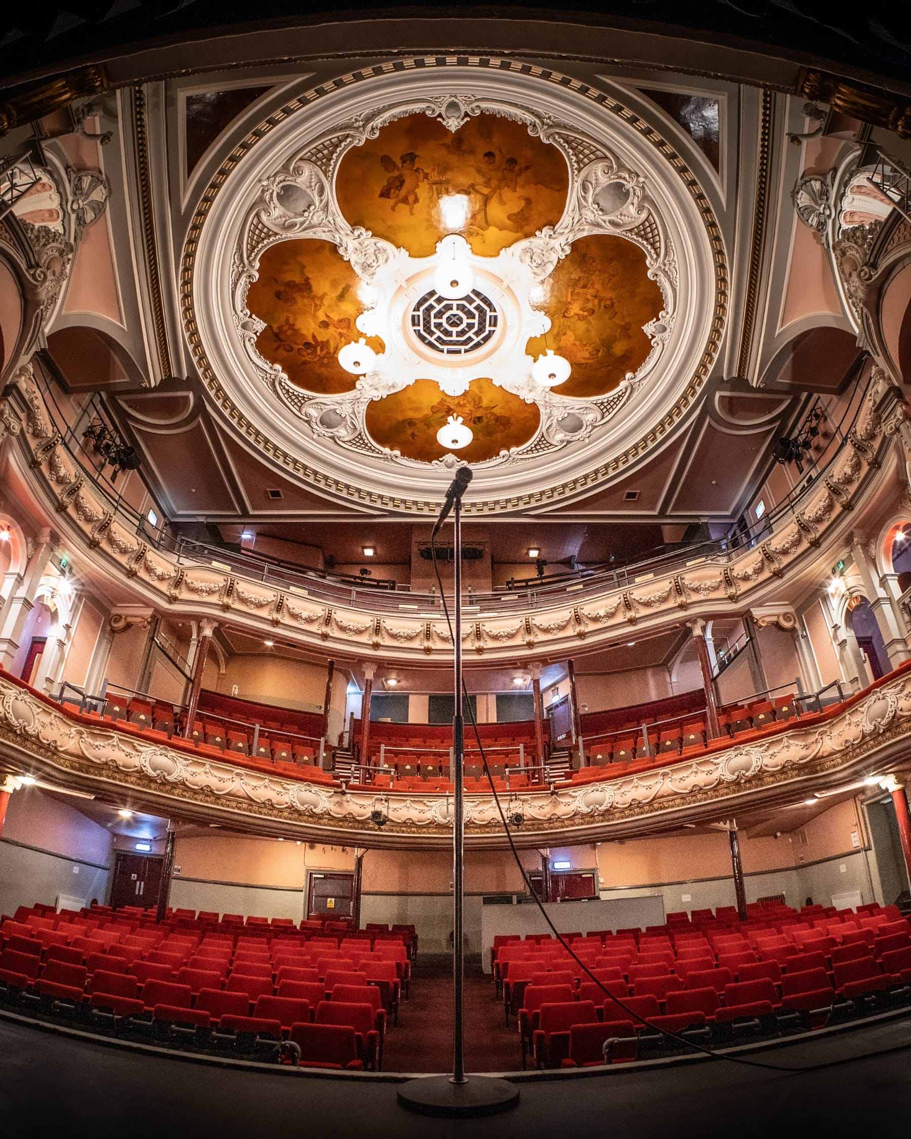 View from the stage of the Tivoli Theatre showing red seats and a decorative ceiling.