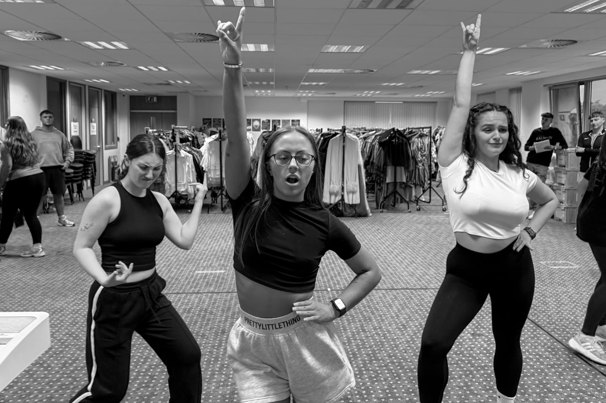 Three dancers pose mid-routine during rehearsal, one with arm raised.