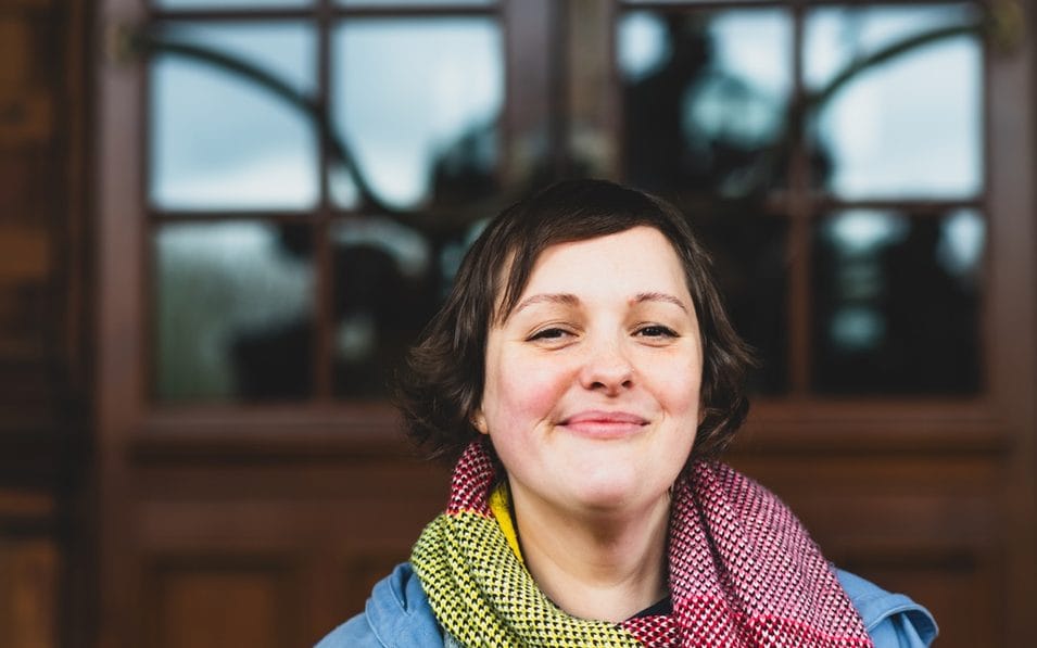 Comedian Josie Long wearing a colourful scarf in a candid outdoor portrait.