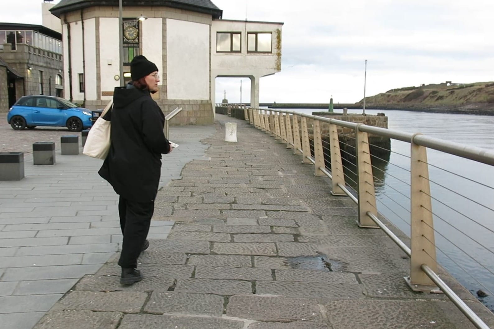 Artist Olesya Ilenok walks by the waterfront in Aberdeen, carrying materials for her project.