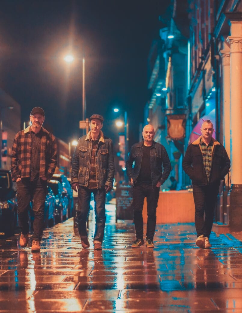 Four members of Aadal walking down a wet city street at night.