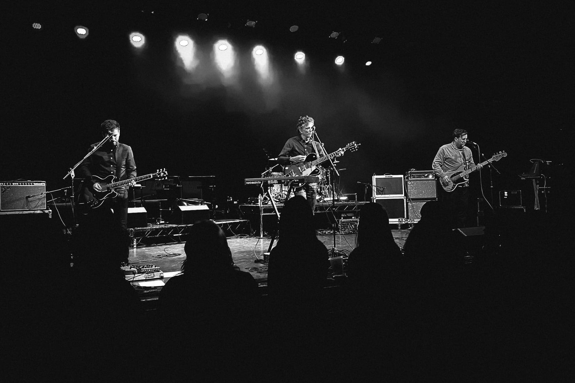 Black and white photo of The Little Kicks playing on stage with guitars.