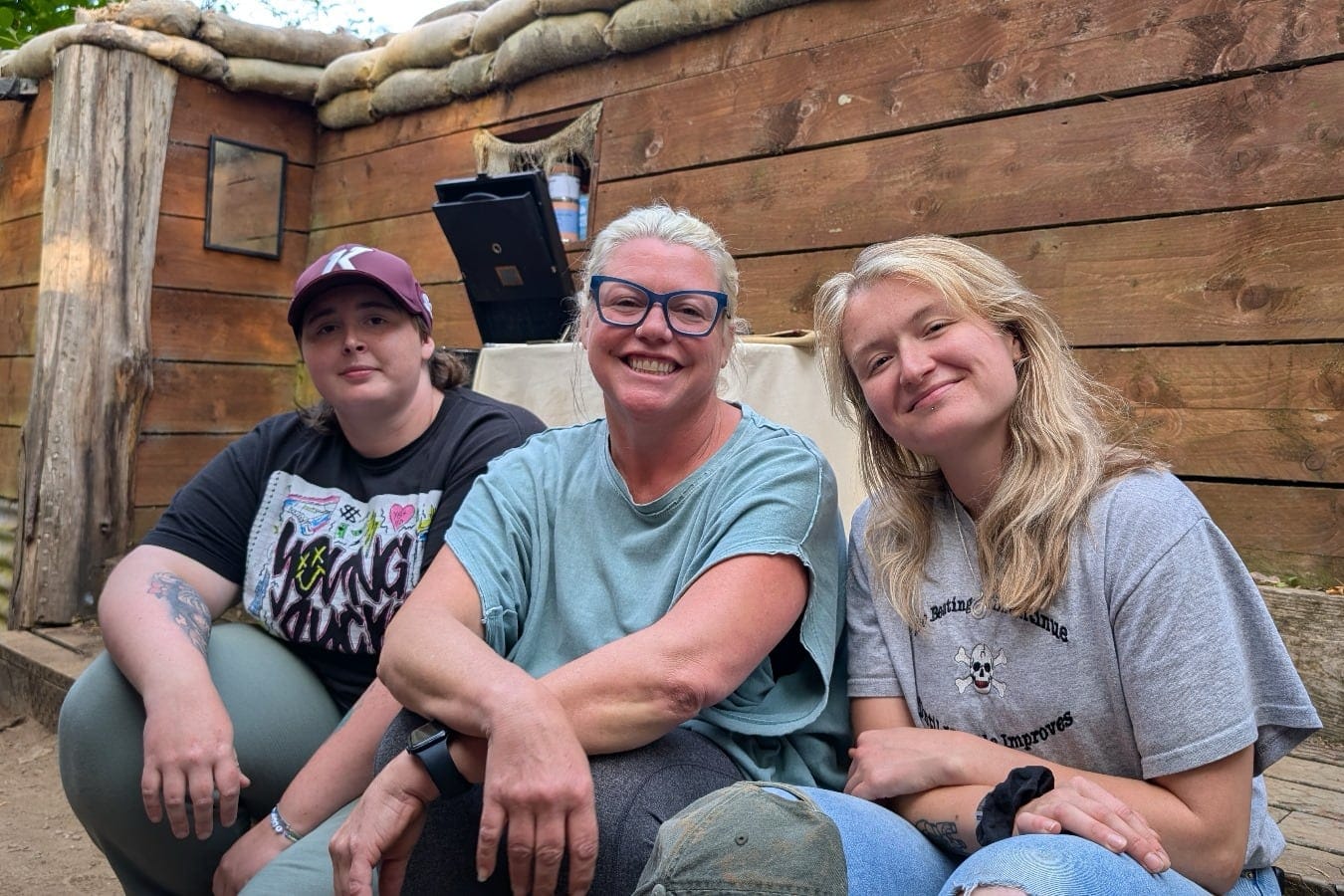 Nicky Nangle, Niki Foy and Phoebe Banks sit smiling together on a trench set.
