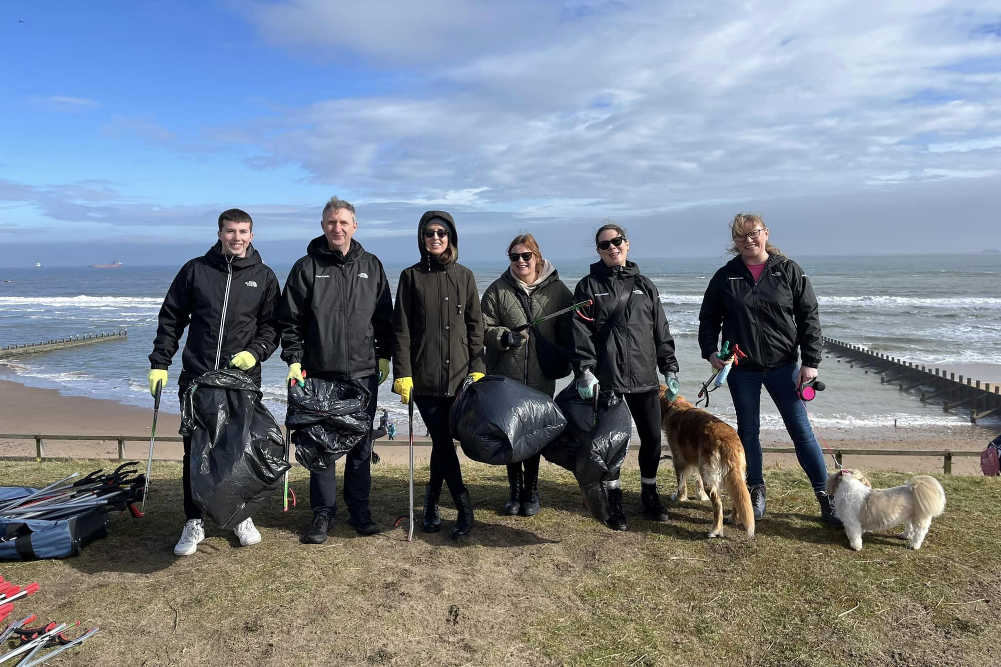Group of volunteers with bin bags and litter pickers during a beach clean in Aberdeen.