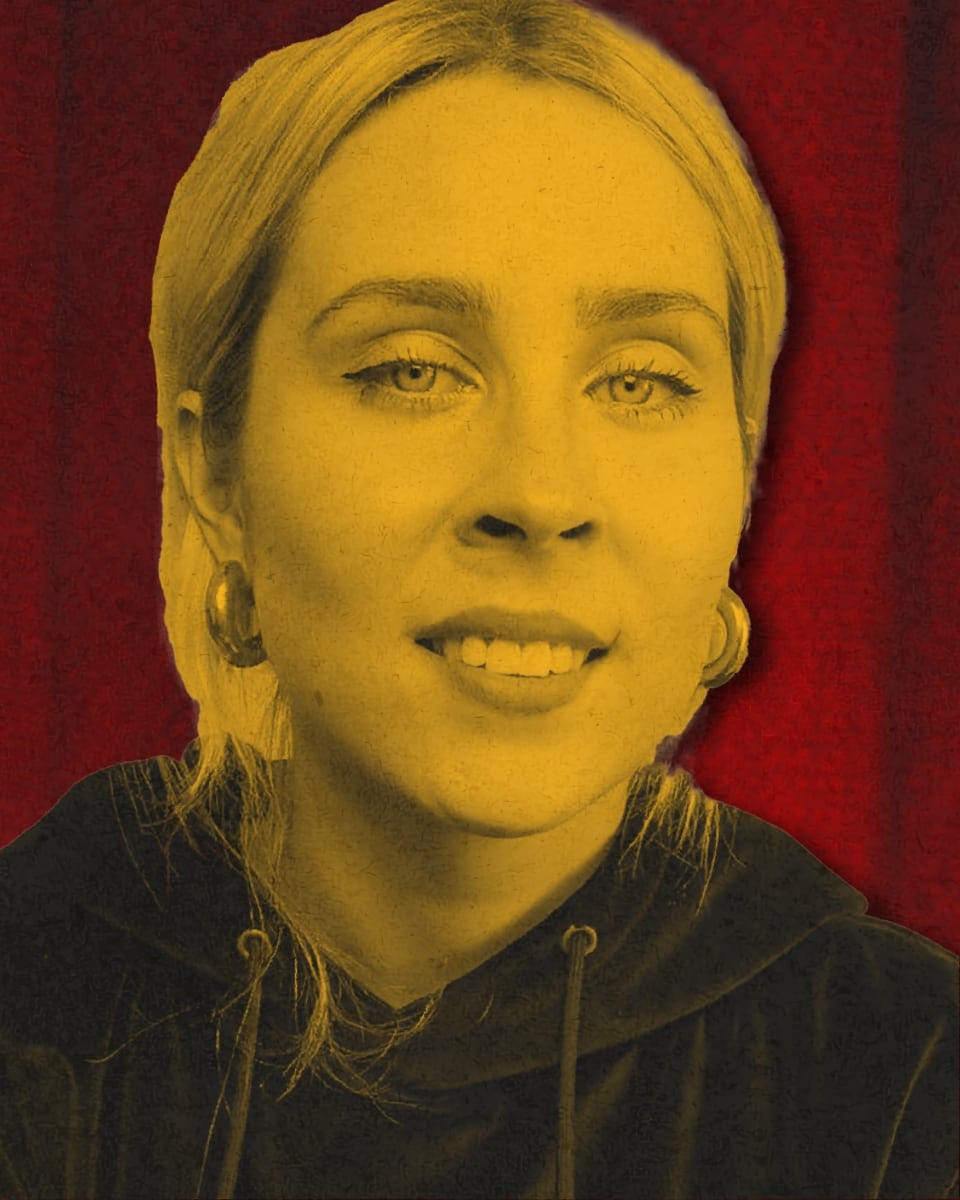 Stylised yellow-toned portrait of Stevie Martin against a red curtain backdrop.