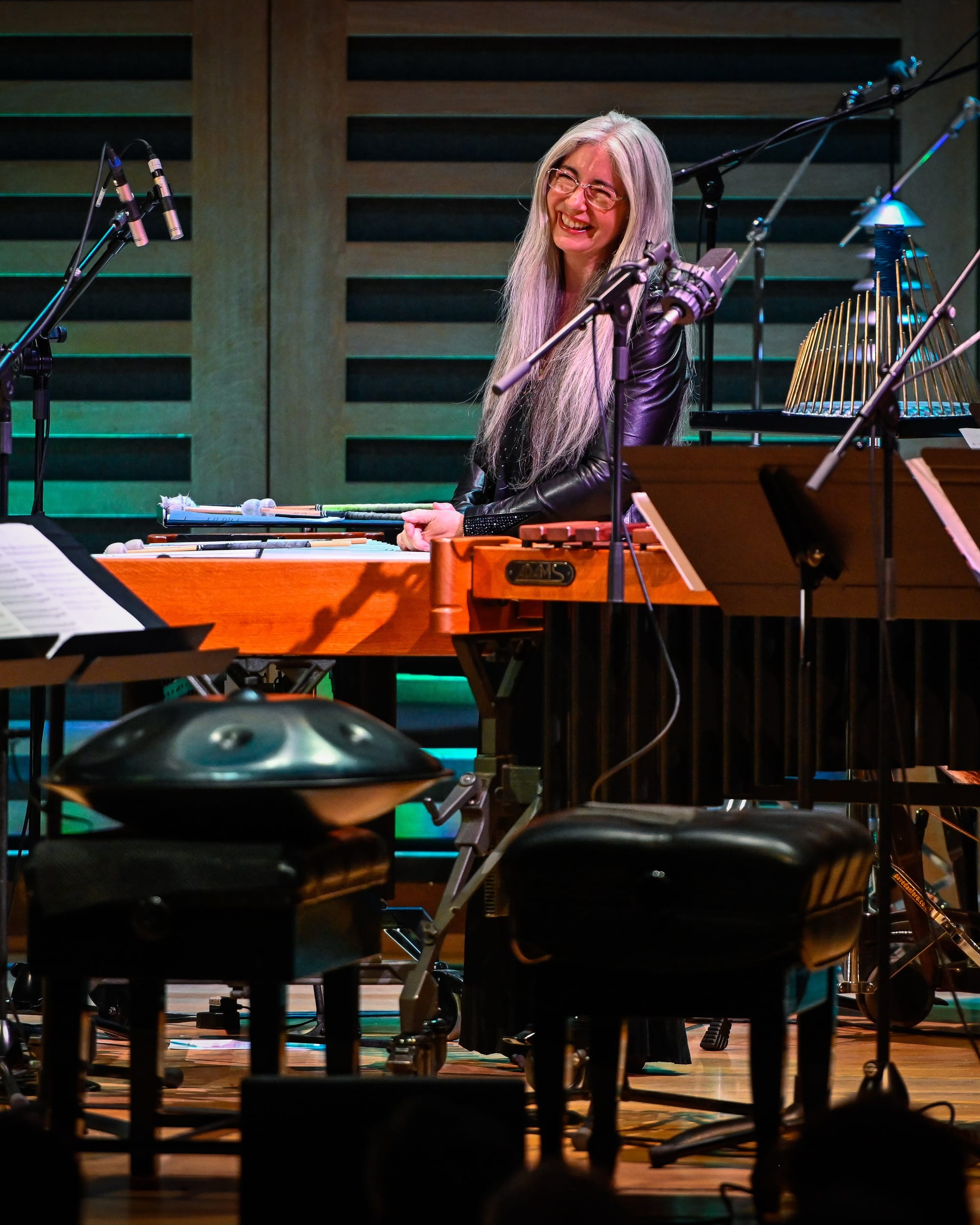 Dame Evelyn Glennie smiling at a marimba on stage, surrounded by percussion instruments