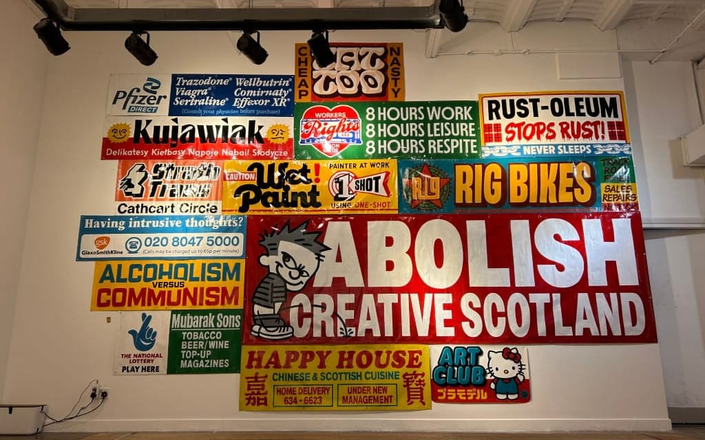 A gallery wall covered in hand-painted signs in various styles and colours.