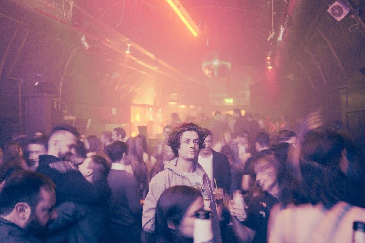 A packed, hazy dance floor under a disco ball at a club night