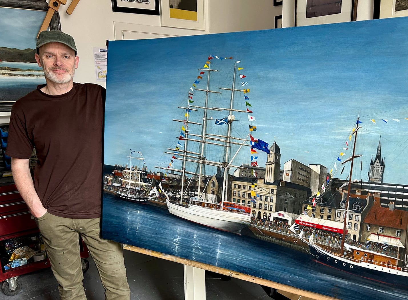 Clive Ramage standing beside his finished Festival of Sail painting