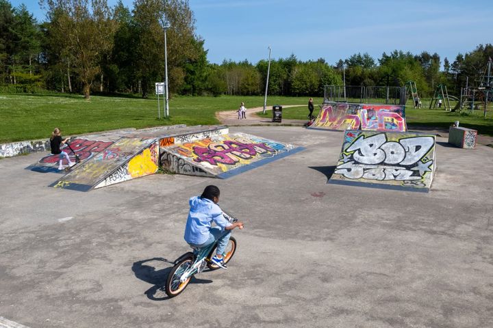 Kids play on a skatepark with colourful graffiti on the ramps