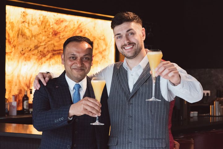 Parveen Sood and Stefano Spinello Fusco holding orange cocktails and smiling at Glenhouse Aberdeen