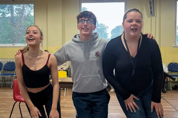 Three Phoenix Youth cast members sing together in a rehearsal room, mid-performance and full of energy.