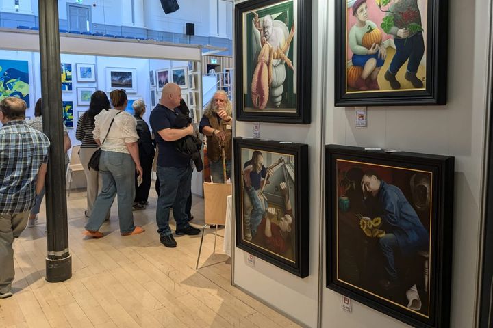 Visitors looking at framed paintings and chatting at Aberdeen Art Fair